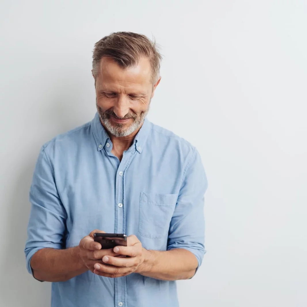 man looking down at his phone smiling